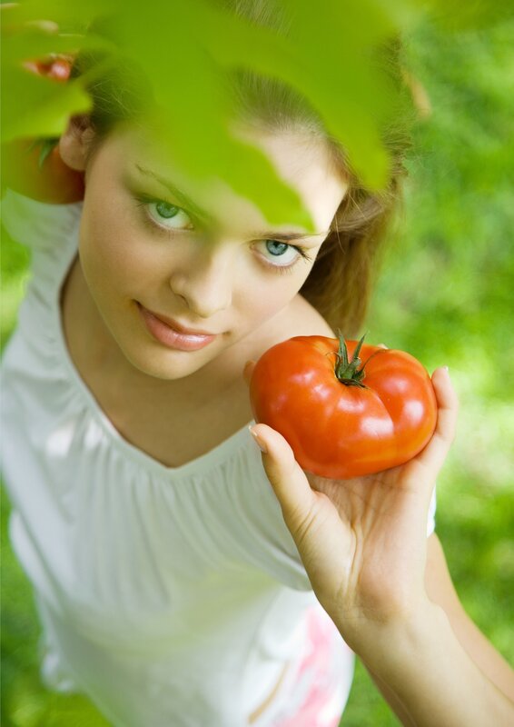 woman holding tomato in garden