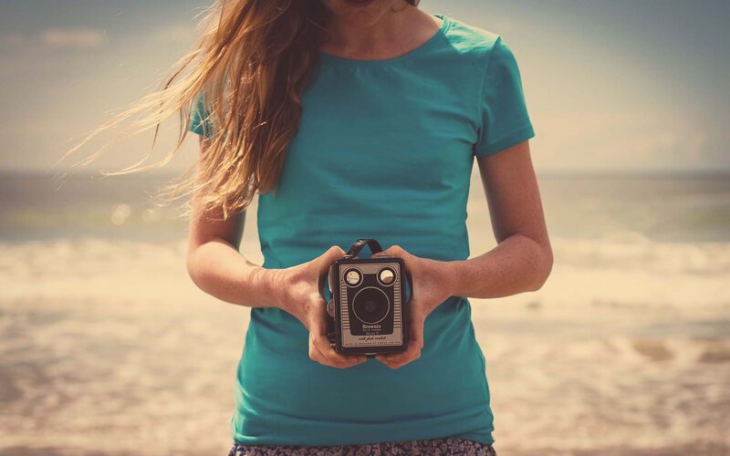 woman holding vintage camera at beach
