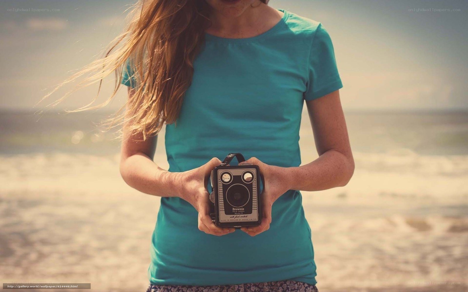 woman holding vintage camera at beach