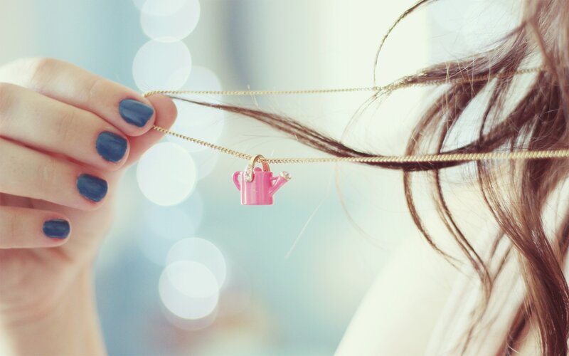 woman holding watering can necklace
