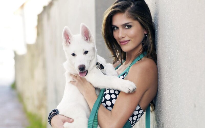 woman holding white puppy