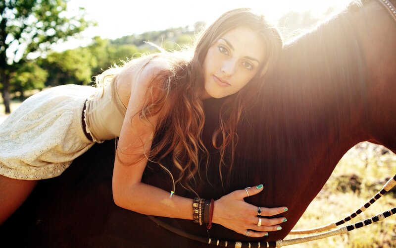 woman hugging horse in sunlight