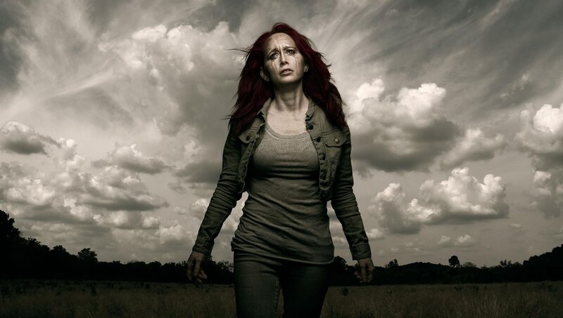 woman in a field under stormy sky