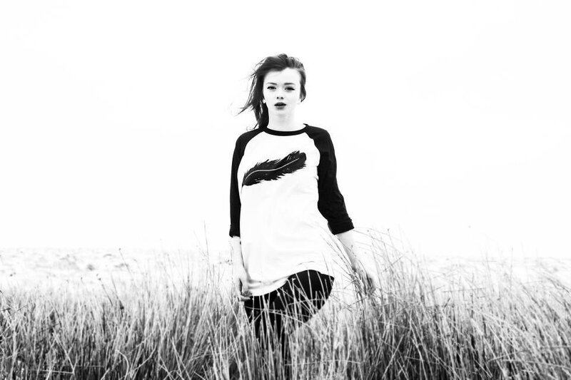 woman in a field with feather shirt