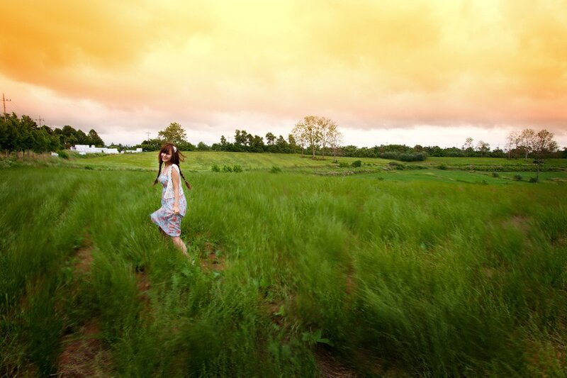 Woman in a green field at sunset
