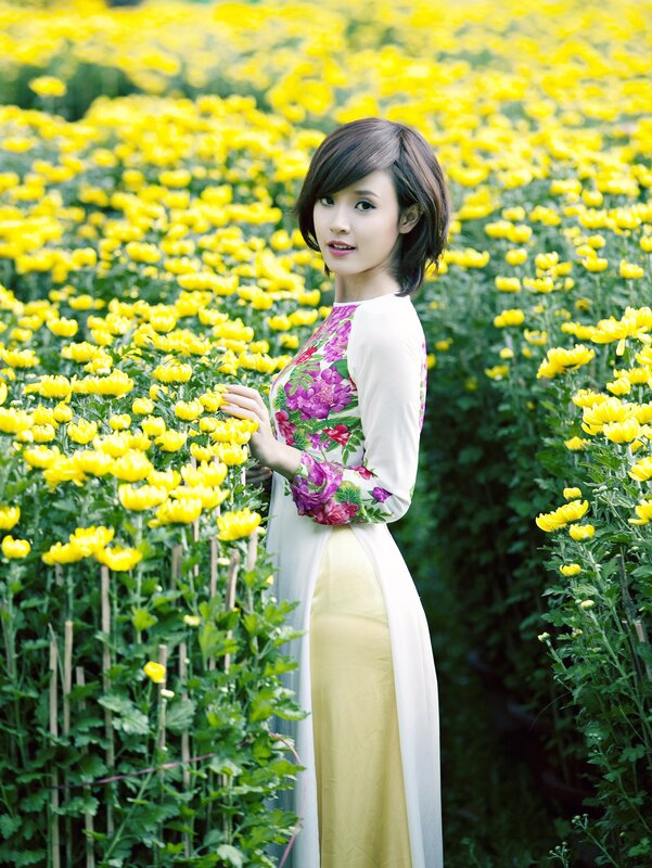 Woman in ao dai among yellow flowers