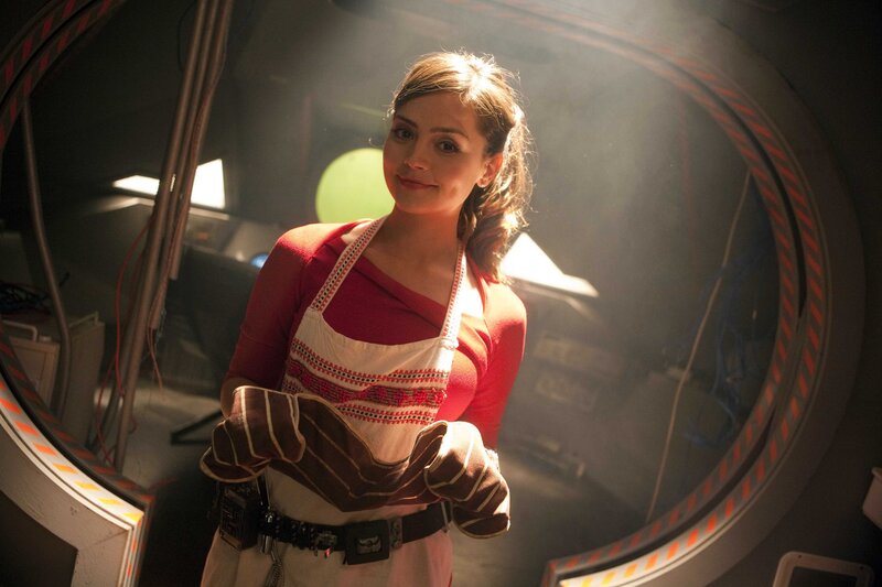 Woman in apron holding oven mitts