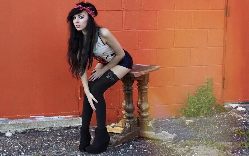 woman in bandana posing by orange wall