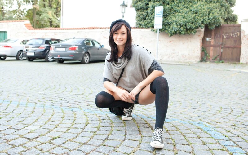 woman in beanie crouching on cobblestones