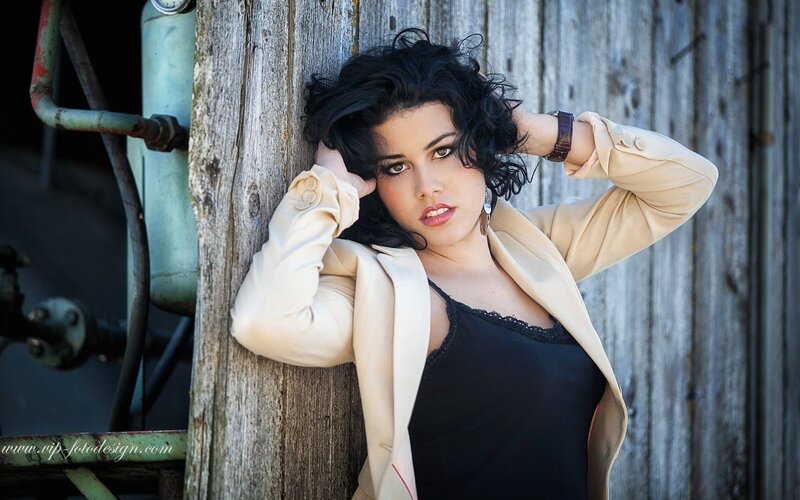 woman in beige coat leaning on wood