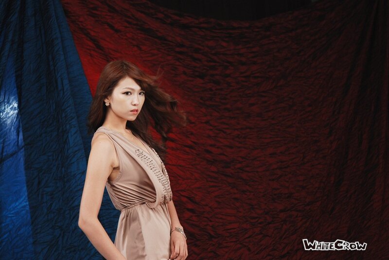 woman in beige dress against red and blue backdrop