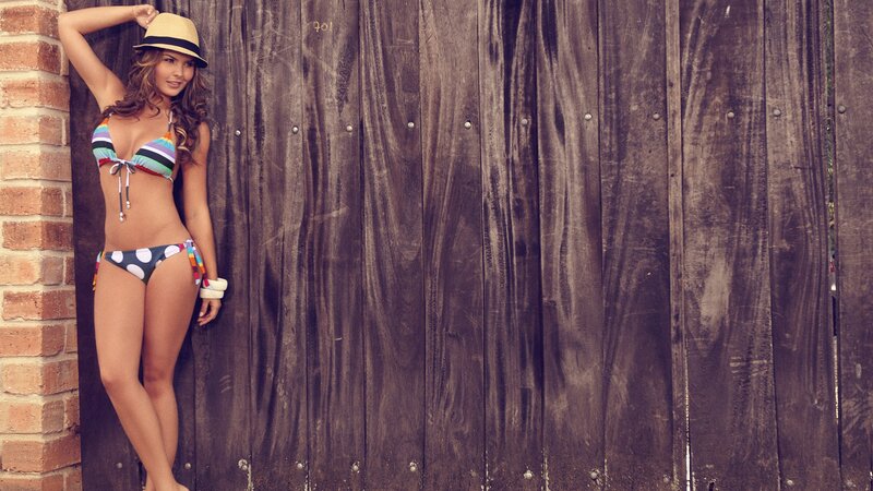woman in bikini by wooden wall