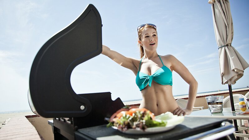 Woman in bikini grilling outdoors