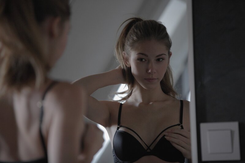 woman in black bra looking in mirror