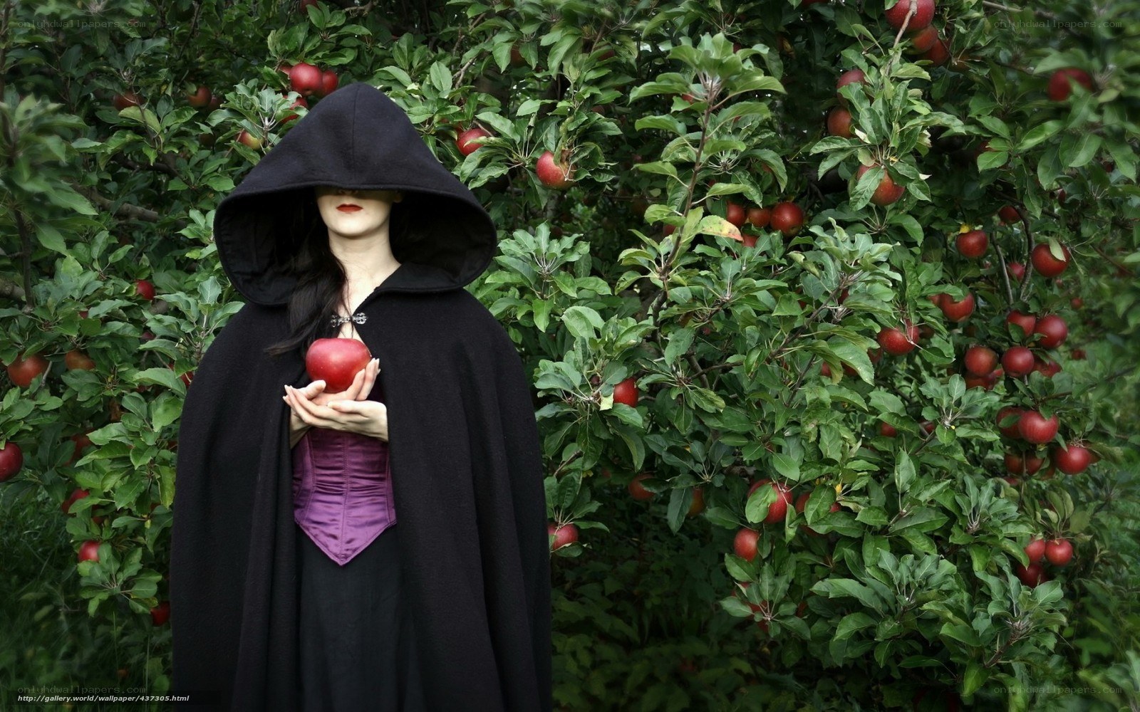 Woman in black cloak holding apple