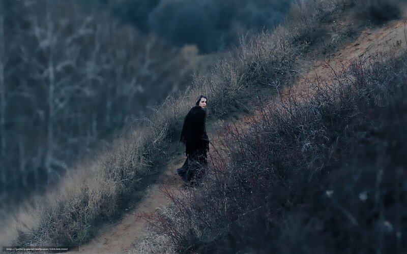 woman in black cloak on hillside