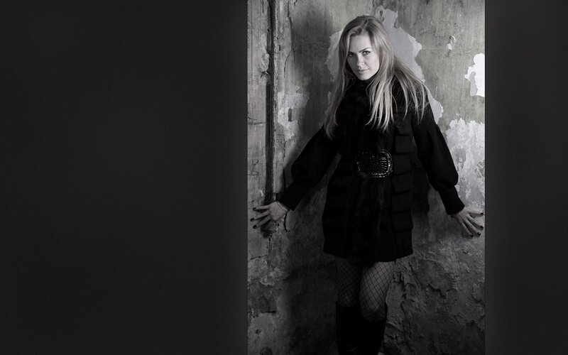 woman in black coat against wall