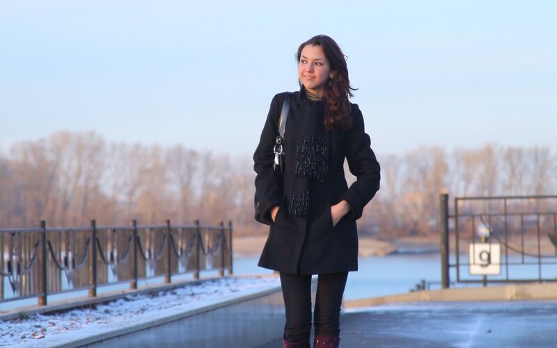 Woman in black coat by river
