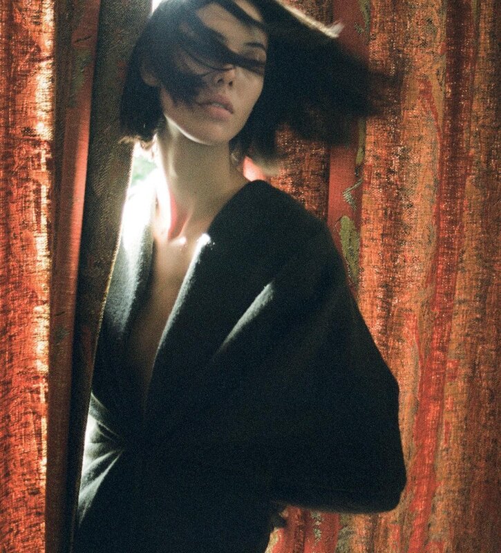 woman in black coat by window