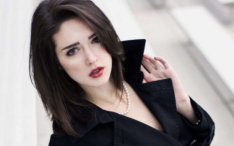woman in black coat with pearls
