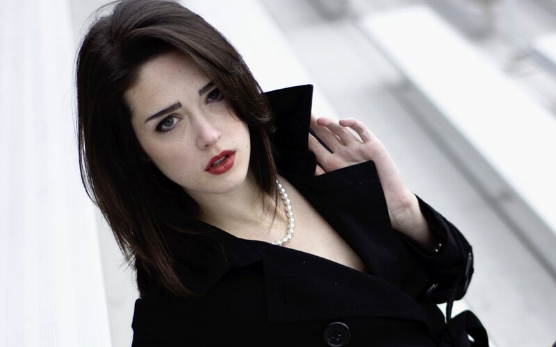 woman in black coat with pearls