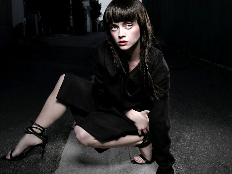 woman in black crouching on street