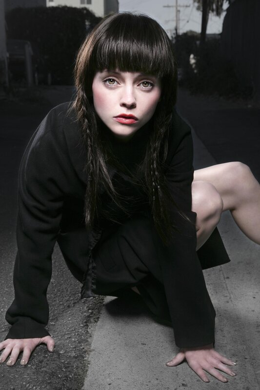woman in black crouching on street