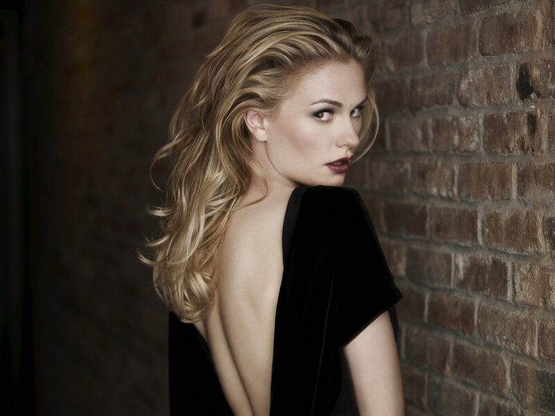 woman in black dress against brick wall