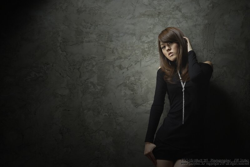 woman in black dress against concrete wall