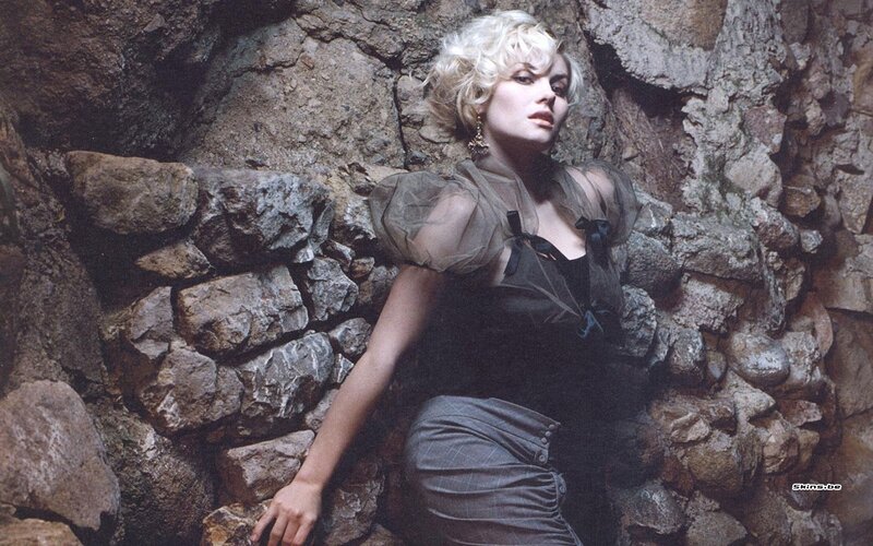woman in black dress against stone wall