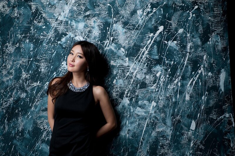 woman in black dress against textured wall