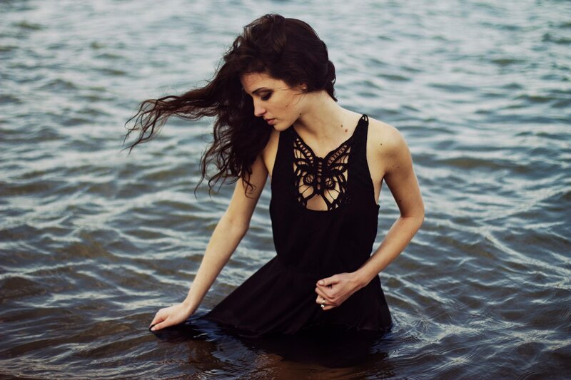 woman in black dress at water's edge
