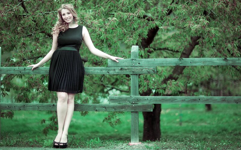 woman in black dress by fence