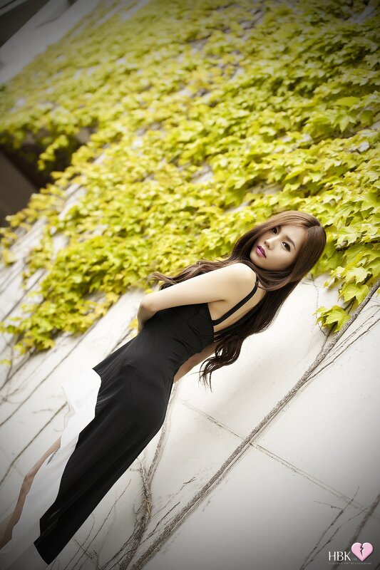 woman in black dress by ivy wall