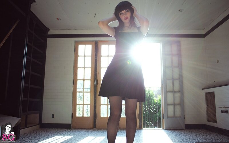 woman in black dress by sunlit door