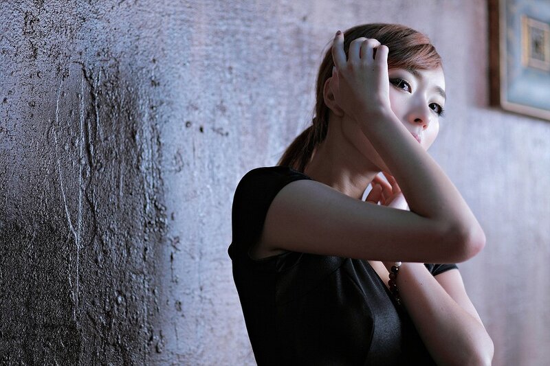 woman in black dress by textured wall