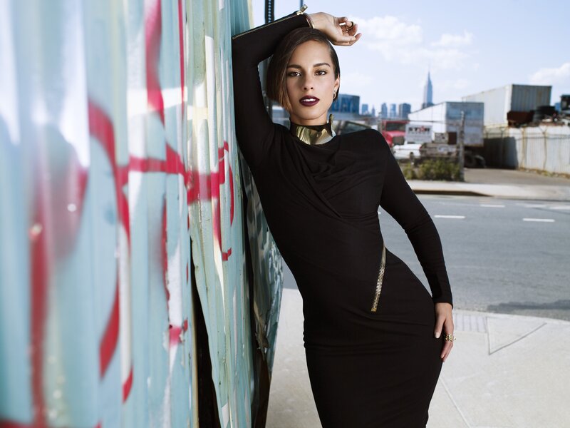 woman in black dress leaning on wall