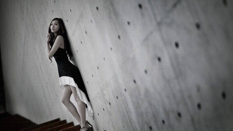 woman in black dress leaning on wall