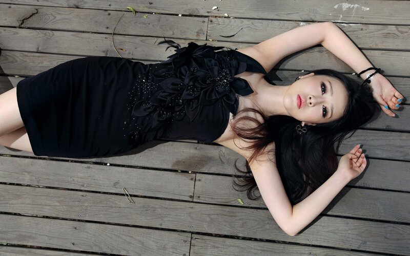 woman in black dress lying on wood