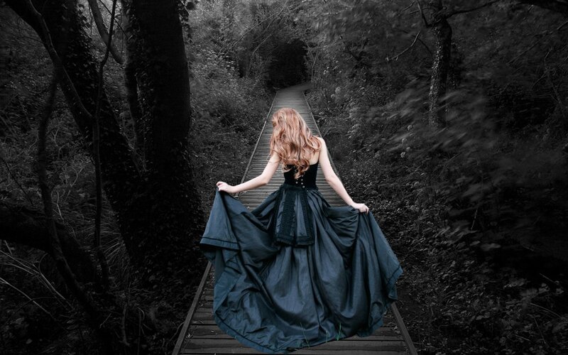 Woman in black dress on forest path