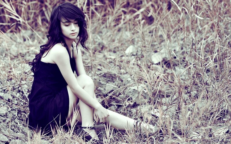 woman in black dress sitting in field