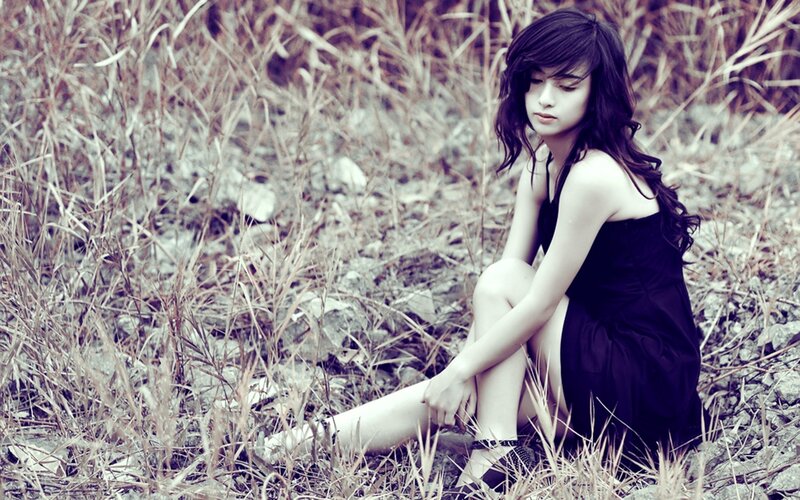 woman in black dress sitting in grass