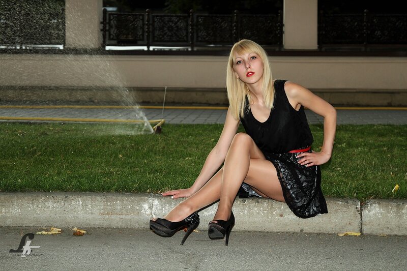 Woman in black dress sitting on curb