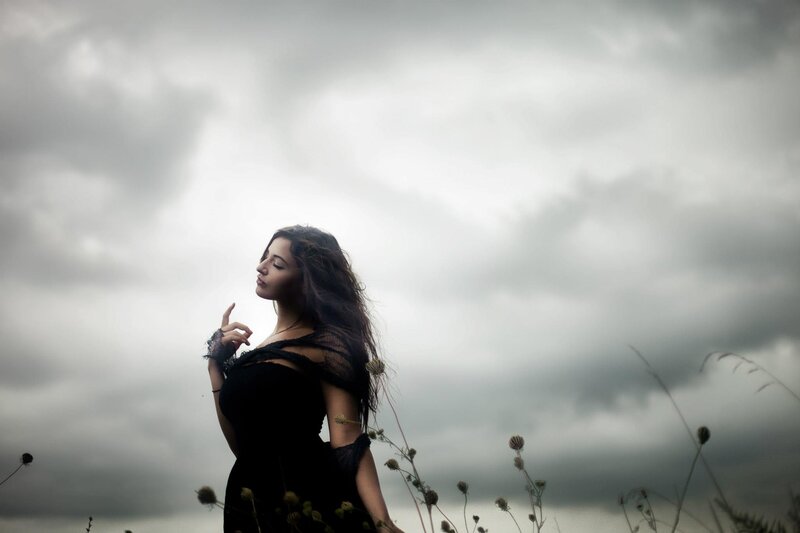 woman in black dress under cloudy sky