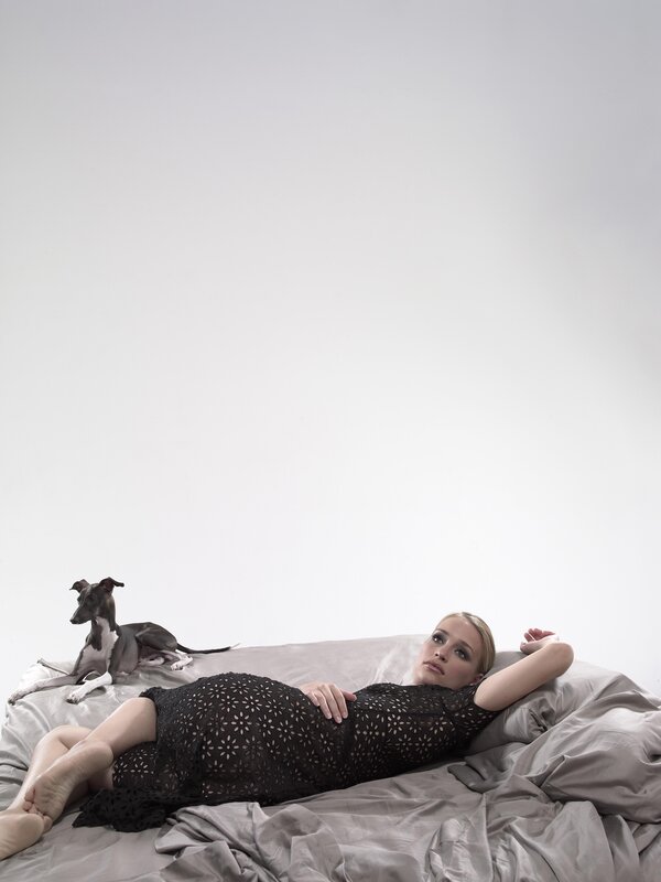 Woman in black dress with dog on bed