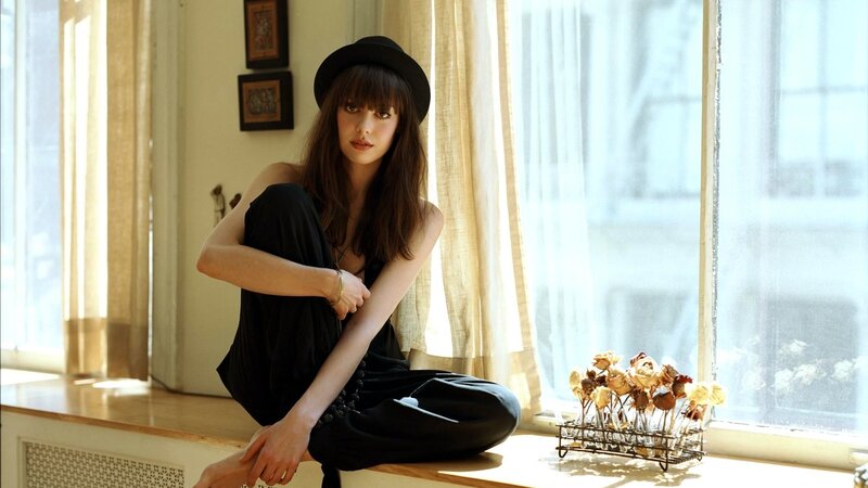 woman in black hat by window