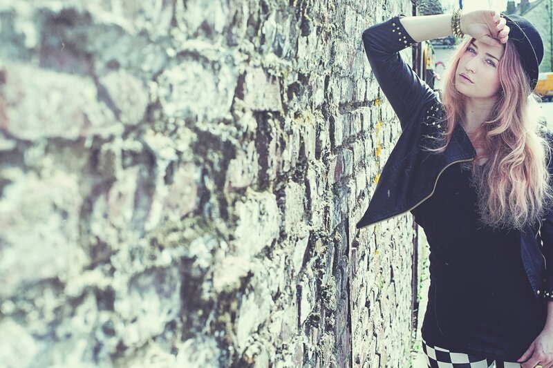 woman in black jacket by stone wall