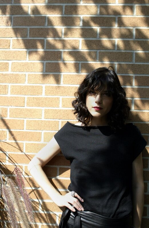 woman in black top against brick wall