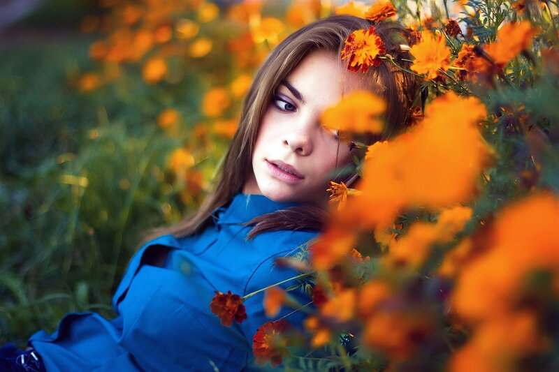 woman in blue among orange flowers
