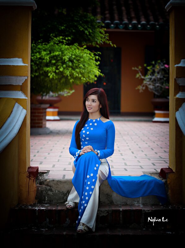 Woman in blue ao dai sitting on steps